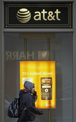 A pedestrian talks on his cell phone while walking past an AT&T ...